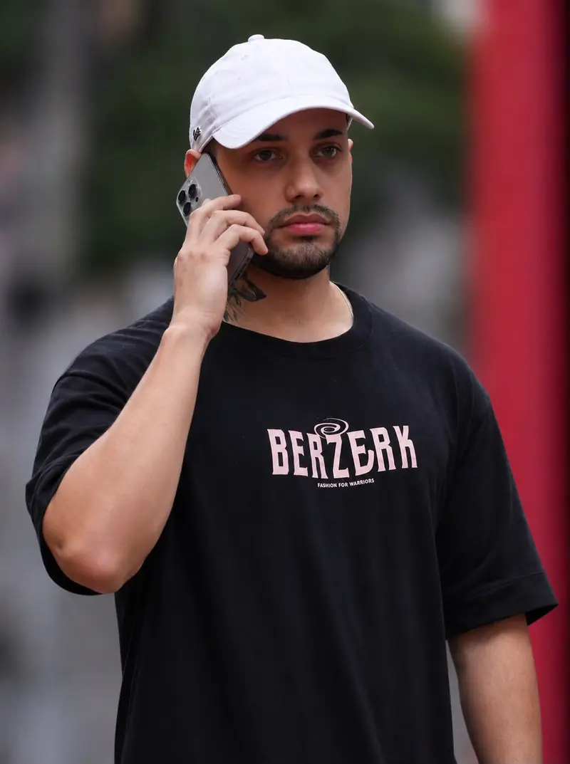 Trader com camiseta preta falando ao telefone na rua